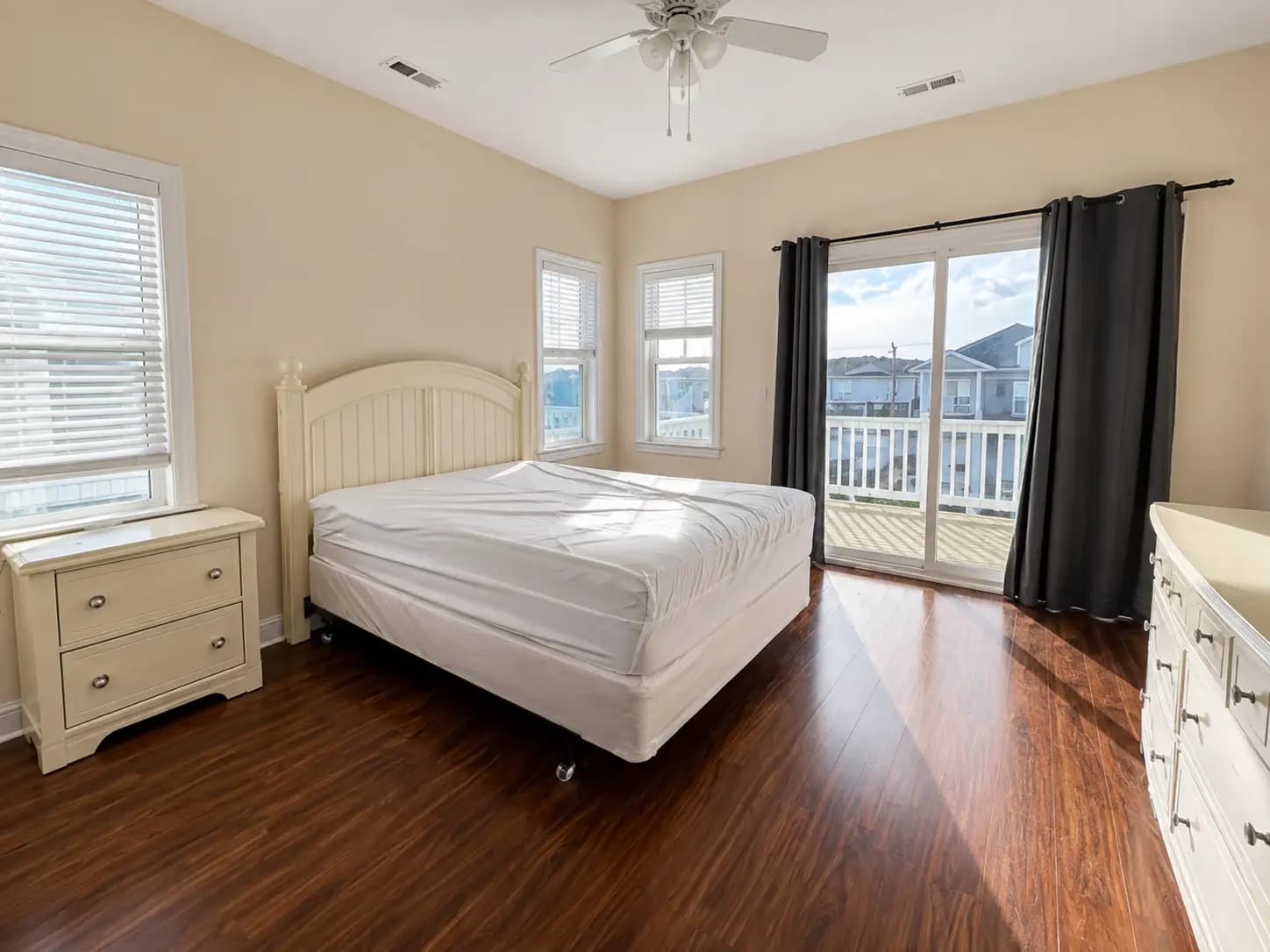 Empty bedroom before Sojourn staging — a bare mattress on a frame, dated furniture, no soft furnishings